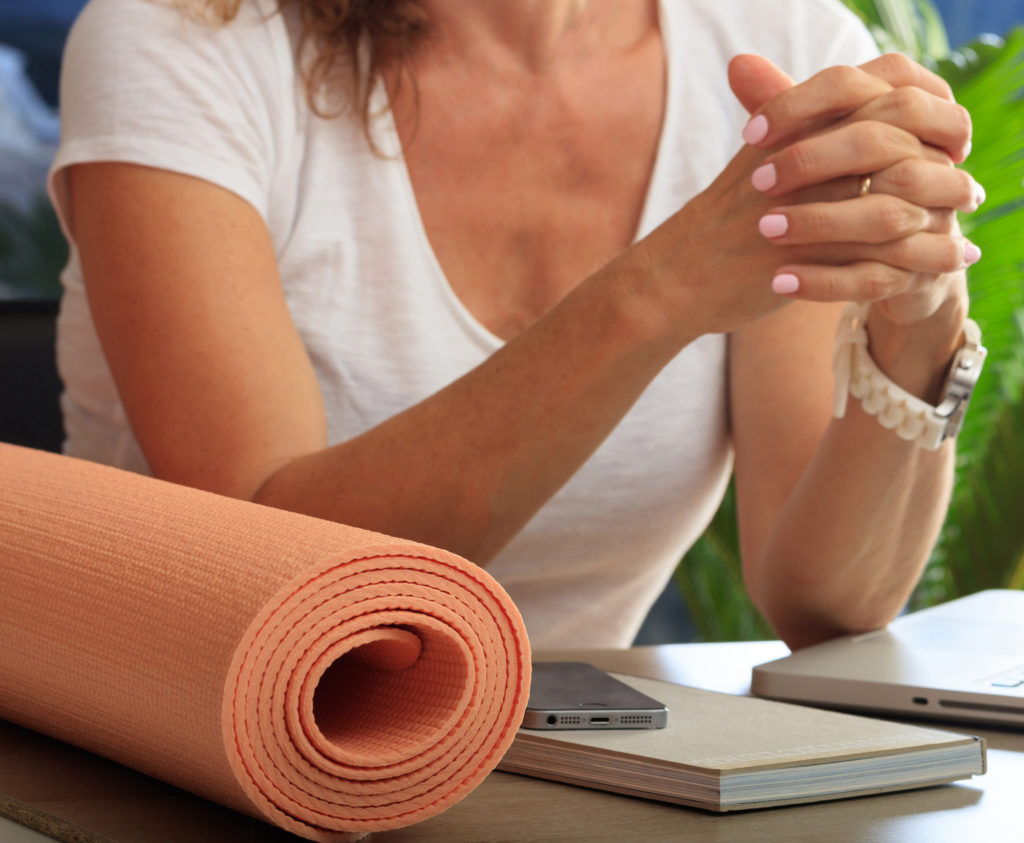 Business and healthy lifestyle concept. Yoga mat on an office desk closeup view, fit woman at workplace